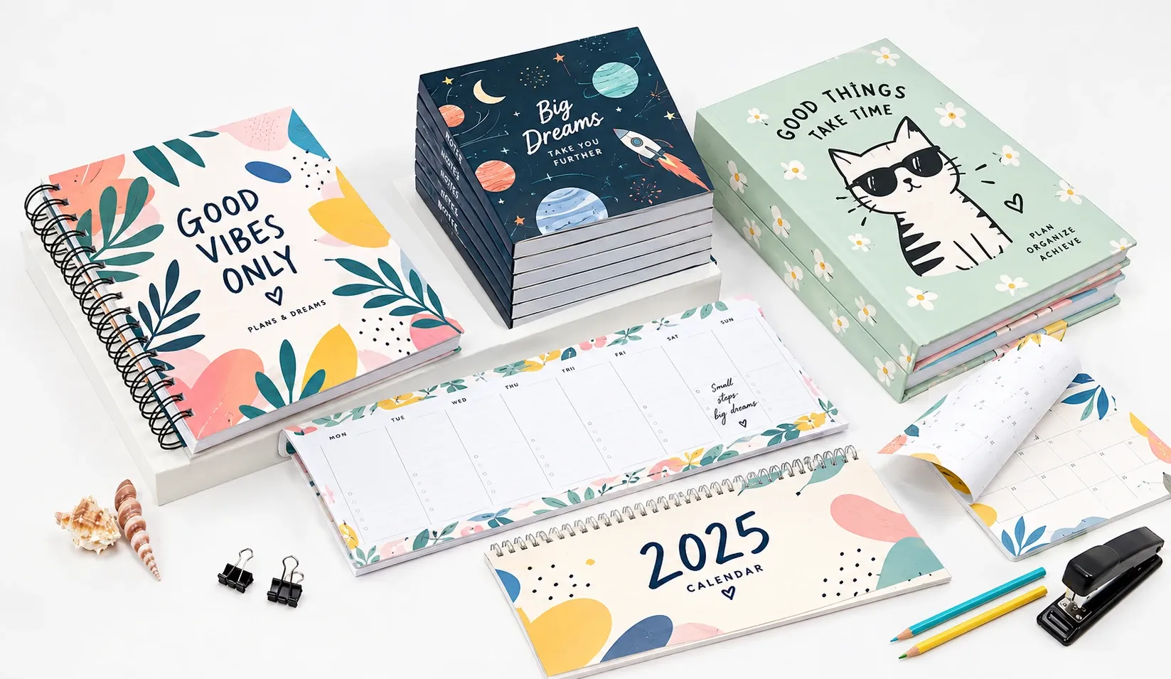 Agendas, cuadernos y calendarios de sobremesa personalizados con diseños ilustrados, colocados sobre una mesa blanca